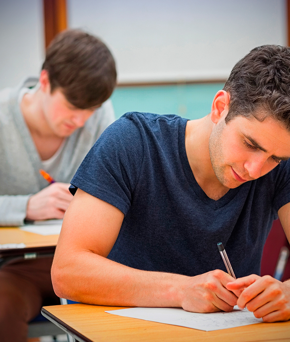 Varios estudiantes realizan un examen de manera individual sentados en sus respectivos pupitres