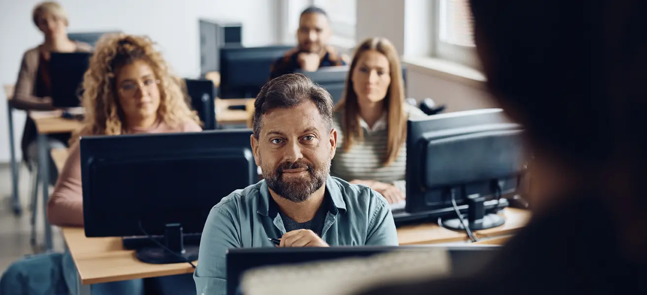 Imagen personas en un aula con ordenadores y formador